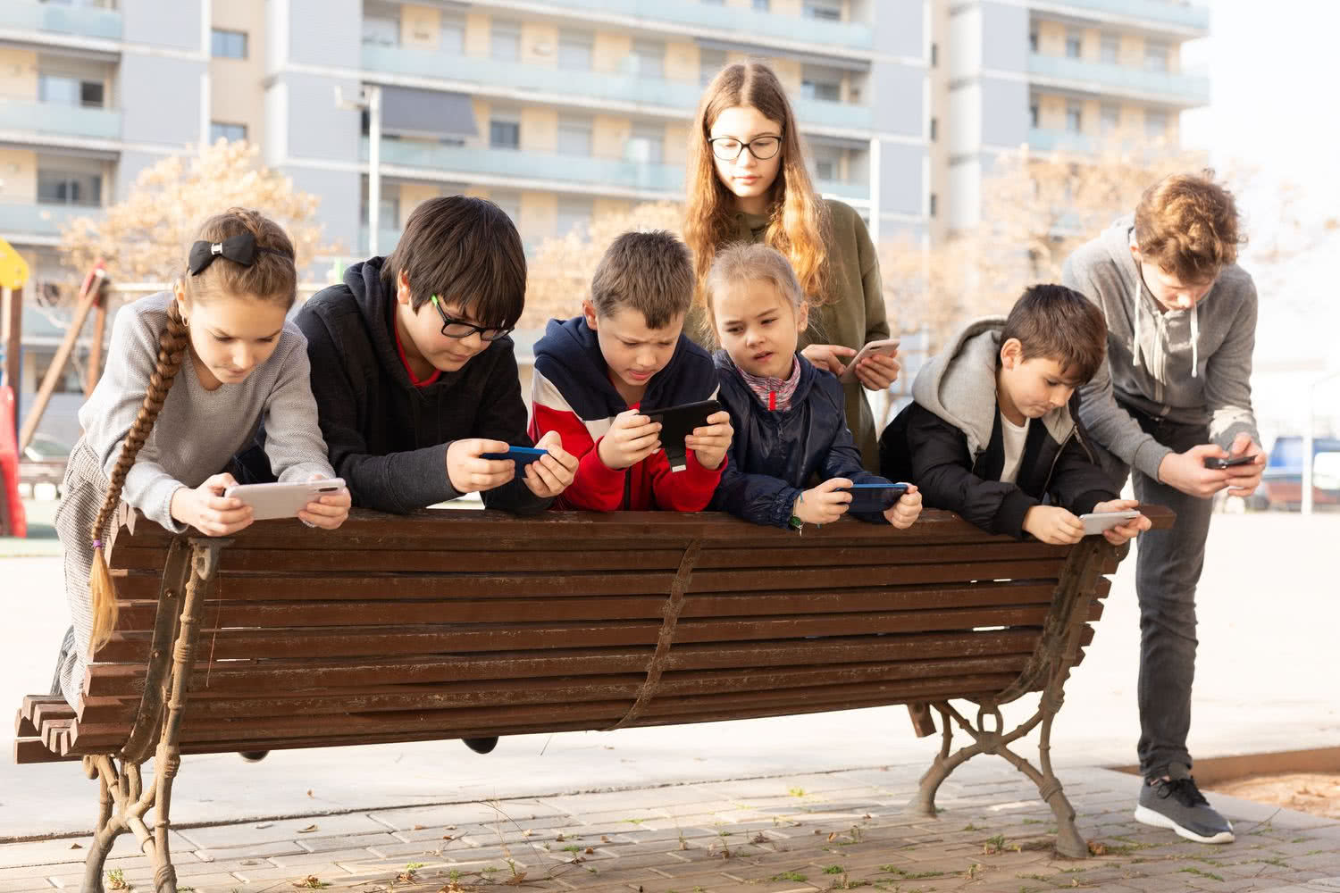 Grupa dzieci grająca na smartfonach poza domem Grupa dzieci grająca na smartfonach poza domem